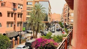 Un carrer residencial amb edificis d'alguns pisos, cotxes aparcats i una palmera.