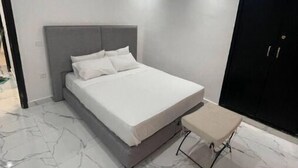 Un dormitori modern amb un llit, una taula petita i un armari.