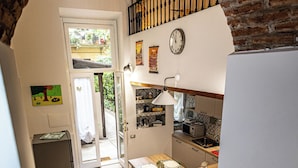 Una cocina con una mesa de madera, un refrigerador y un reloj en la pared.