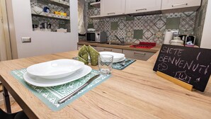 Una cocina con armarios blancos, un microondas y una pizarra con la inscripción 'SICHE BENEVENUT'.