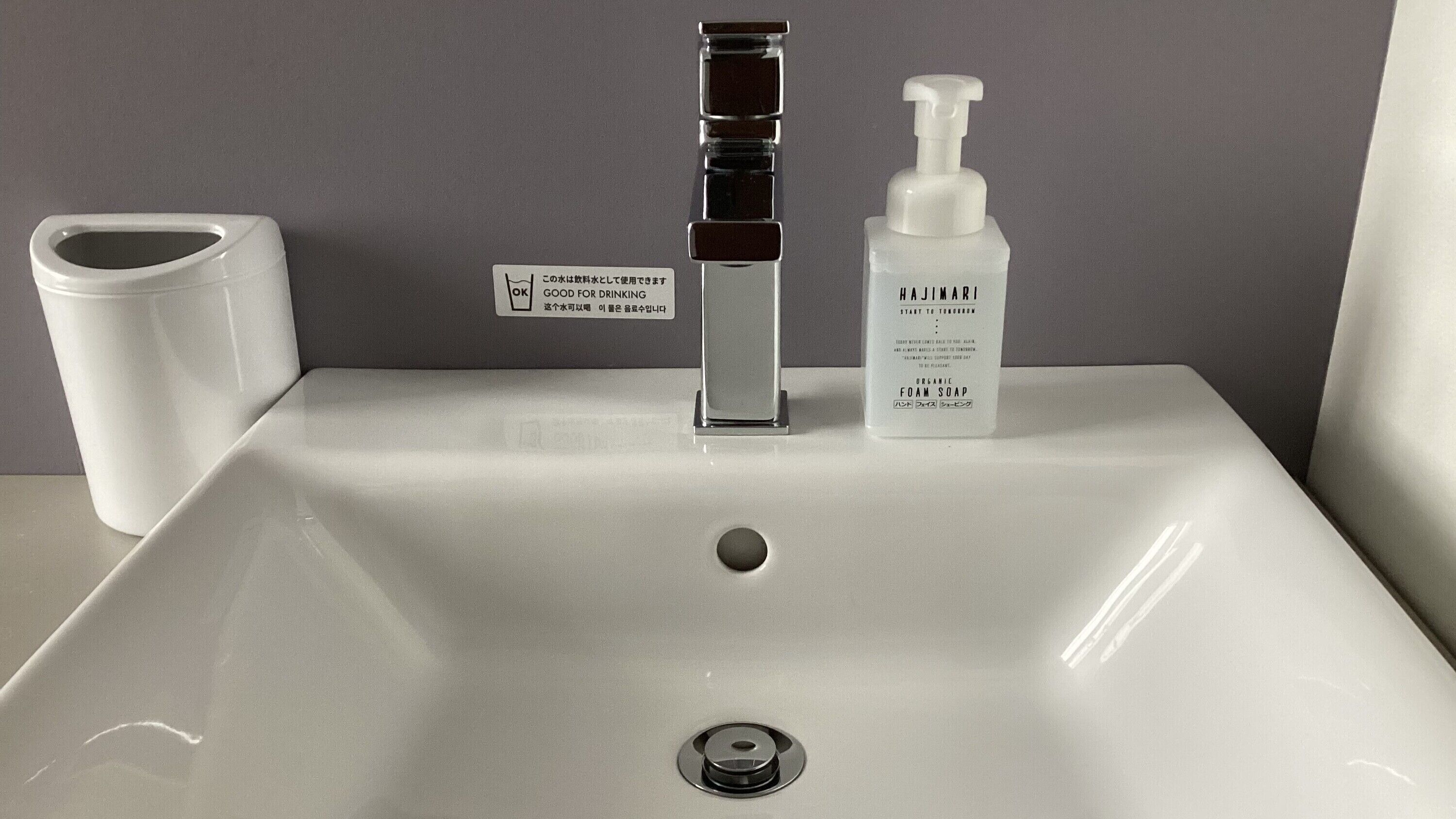 A white bathroom sink with a modern faucet and a soap dispenser.