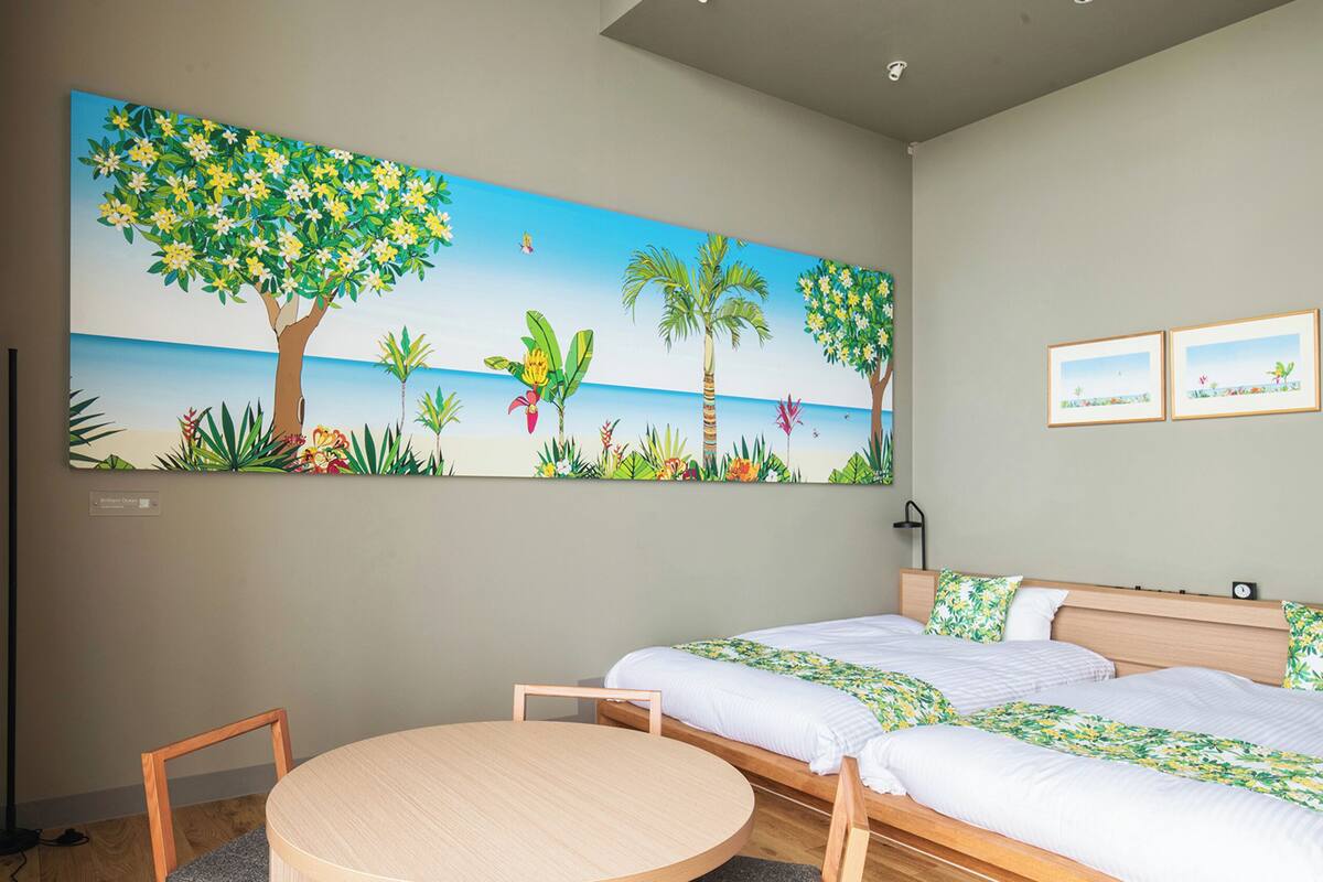 A hotel room with two beds, a round table, and a large tropical-themed painting on the wall.