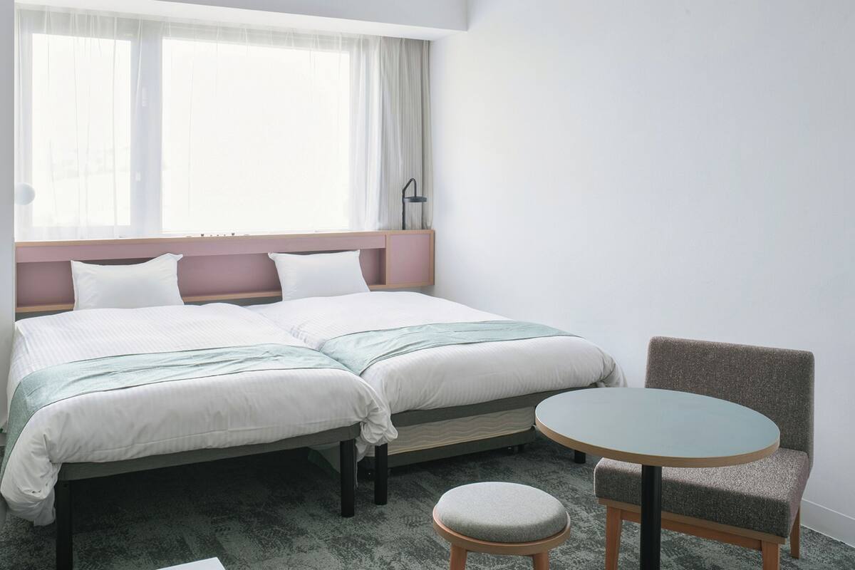 A hotel room with a double bed, a small round table, and a chair.