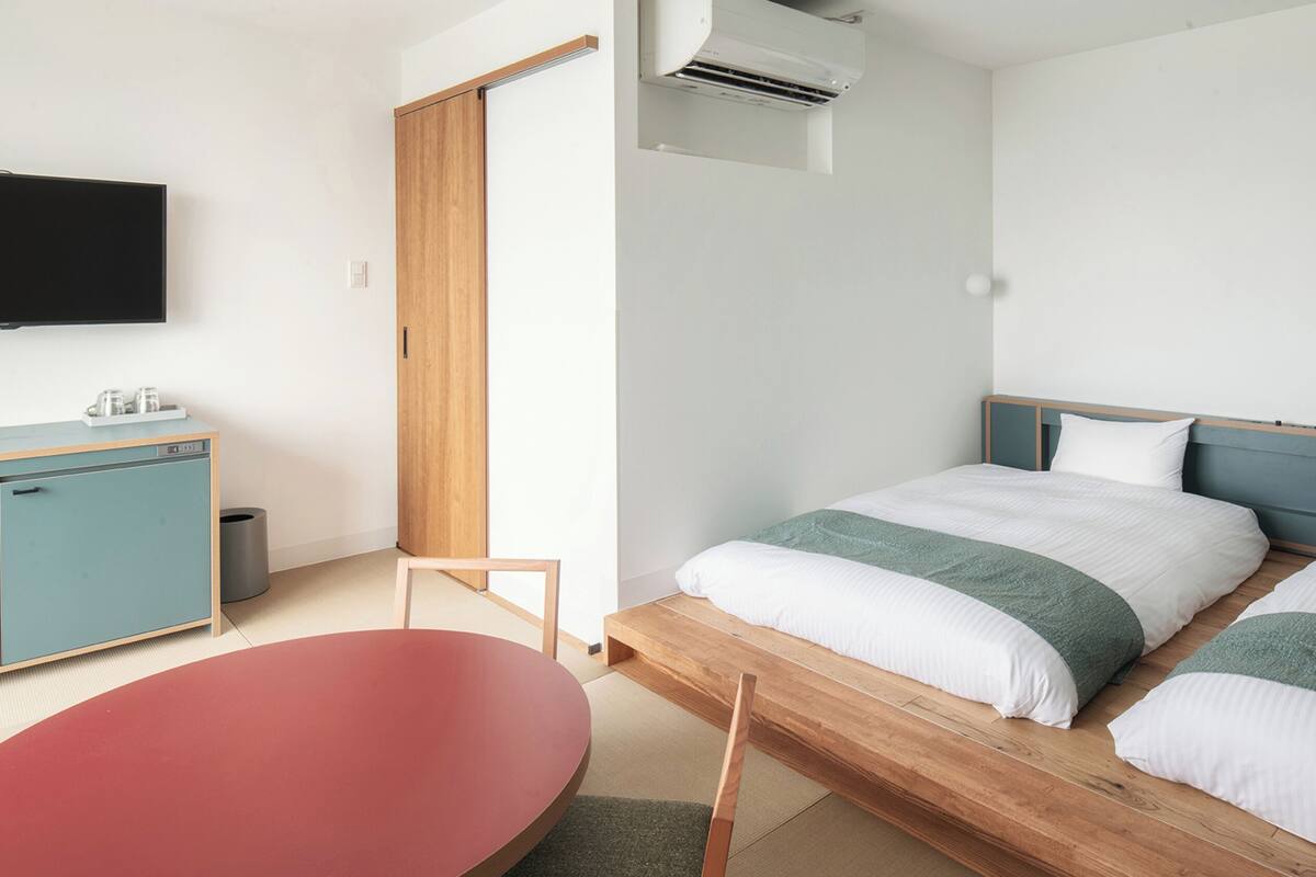 A modern hotel room with a bed, a desk, a chair, and a TV.
