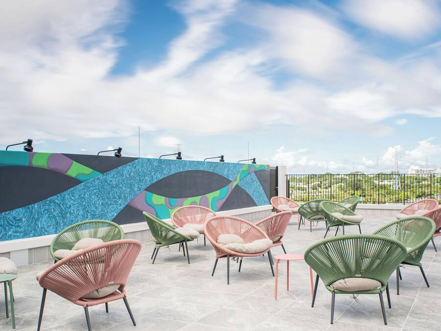 A rooftop terrace with colorful chairs and a mural wall.