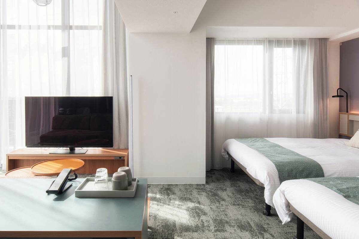 A hotel room with a bed, a TV, a desk with a phone and a tray with toiletries.