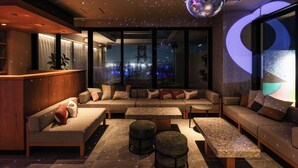 A modern lounge area with a sofa set, ottomans, and a bar counter. - REF Okinawa Arena by VESSEL HOTELS (Okinawa)
