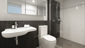 Een moderne badkamer met een wit wastafelmeubel, toilet en een douche met glazen wanden.