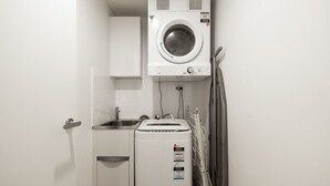Een kleine wasruimte met een wasmachine, een droger en een wasbak.