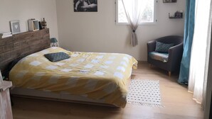 A bedroom with a bed, a chair, a window with curtains, a wooden headboard, and a wall-mounted shelf with items. - Pretty house Aix en provence / Fuveau (Fuveau)