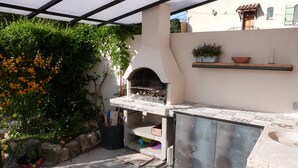 An outdoor kitchen area with a pizza oven, a stone countertop, and a potted plant. - Pretty house Aix en provence / Fuveau (Fuveau)