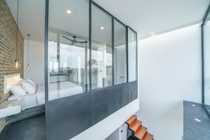 Enjoy a serene view of the outdoors from the large glass wall, featuring a balcony and palm trees.