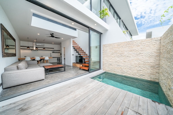 Relax in a spacious living area with a contemporary sofa set and enjoy a kitchen and glass-enclosed outdoor space.