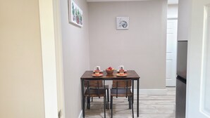 A dining area with a wooden table, four chairs, a bowl of fruit, and two cups with 'ONE MORE' printed on them. - Air Conditioned 2 Bedrooms 1 Bath Apartment, fine decorated, Free Laundry in HPP (Keaau)