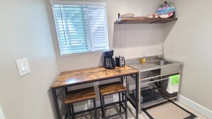 A compact kitchenette with a coffee maker, toaster, and a small shelf with decorative items. - Air Conditioned 2 Bedrooms 1 Bath Apartment, fine decorated, Free Laundry in HPP (Keaau)