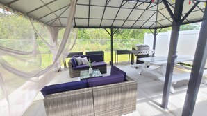An outdoor patio with wicker furniture, a grill, and a table. - Air Conditioned 2 Bedrooms 1 Bath Apartment, fine decorated, Free Laundry in HPP (Keaau)