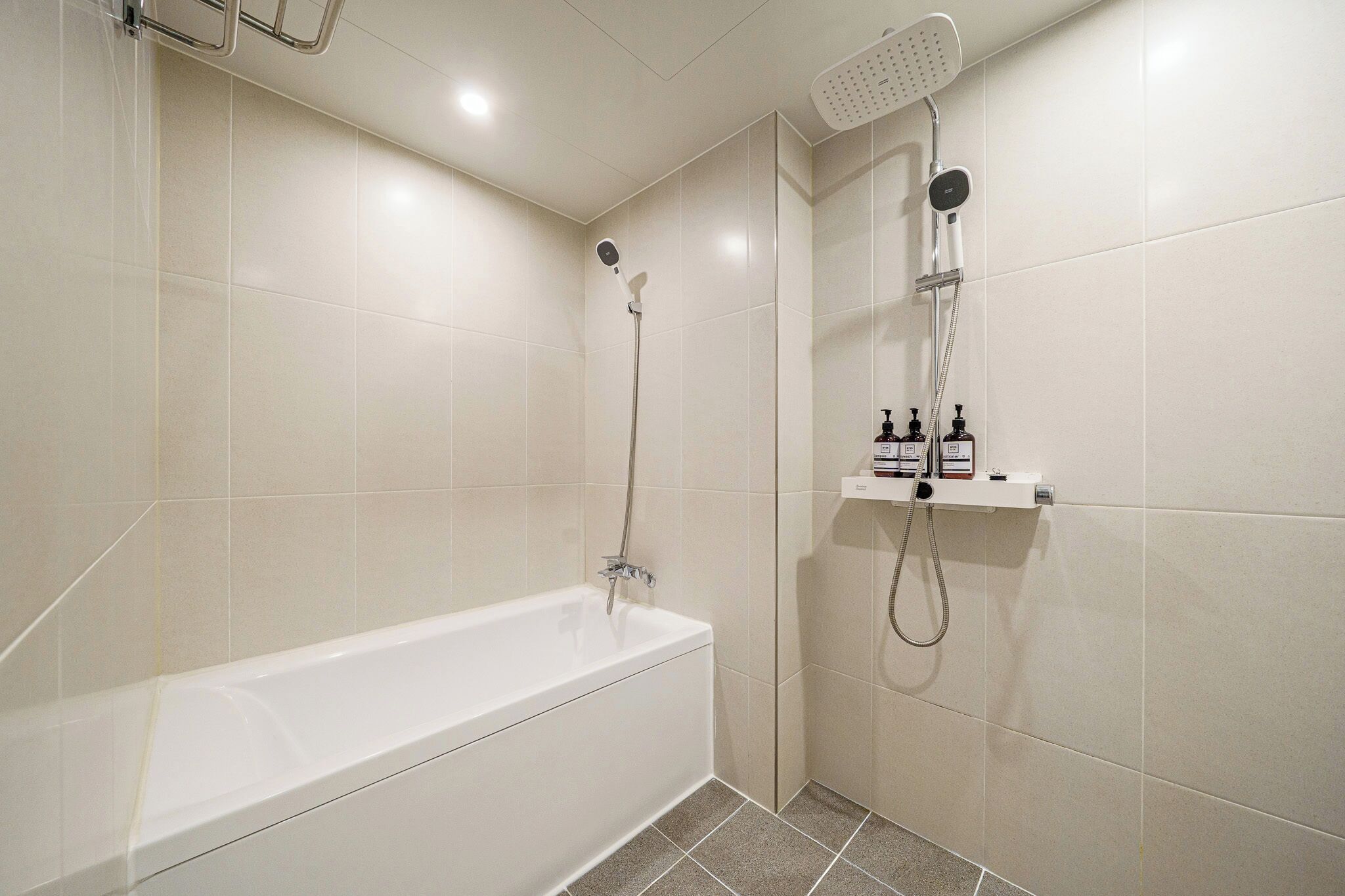 A bathroom with a bathtub, a shower, and a shelf with toiletries.