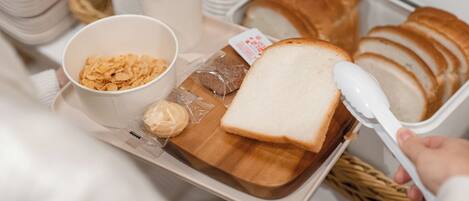 A tray with sliced bread, a bowl of cereal, and a container of butter.
