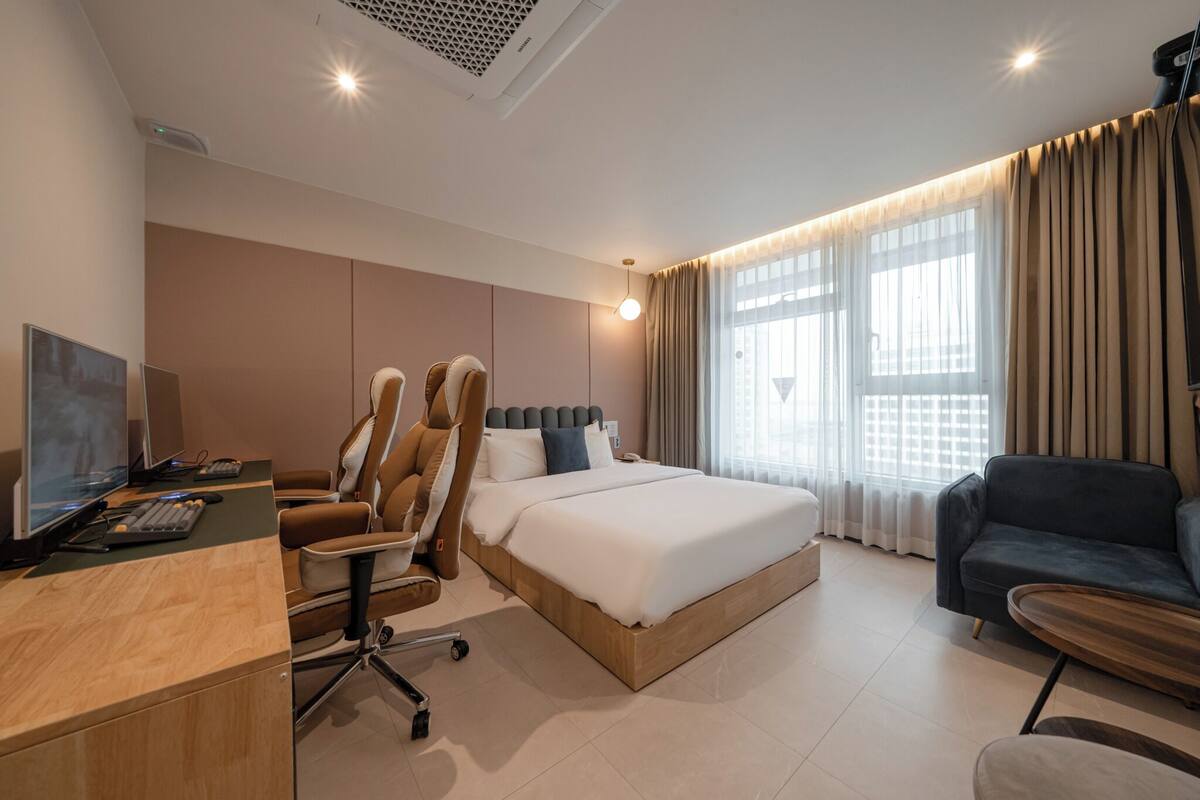 Una habitación de hotel moderna con cama, escritorio, ordenador y zona de estar.