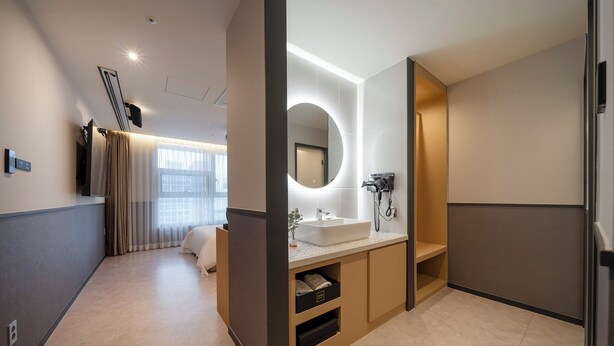 Un baño moderno con un espejo grande, un lavabo y una zona de ducha.