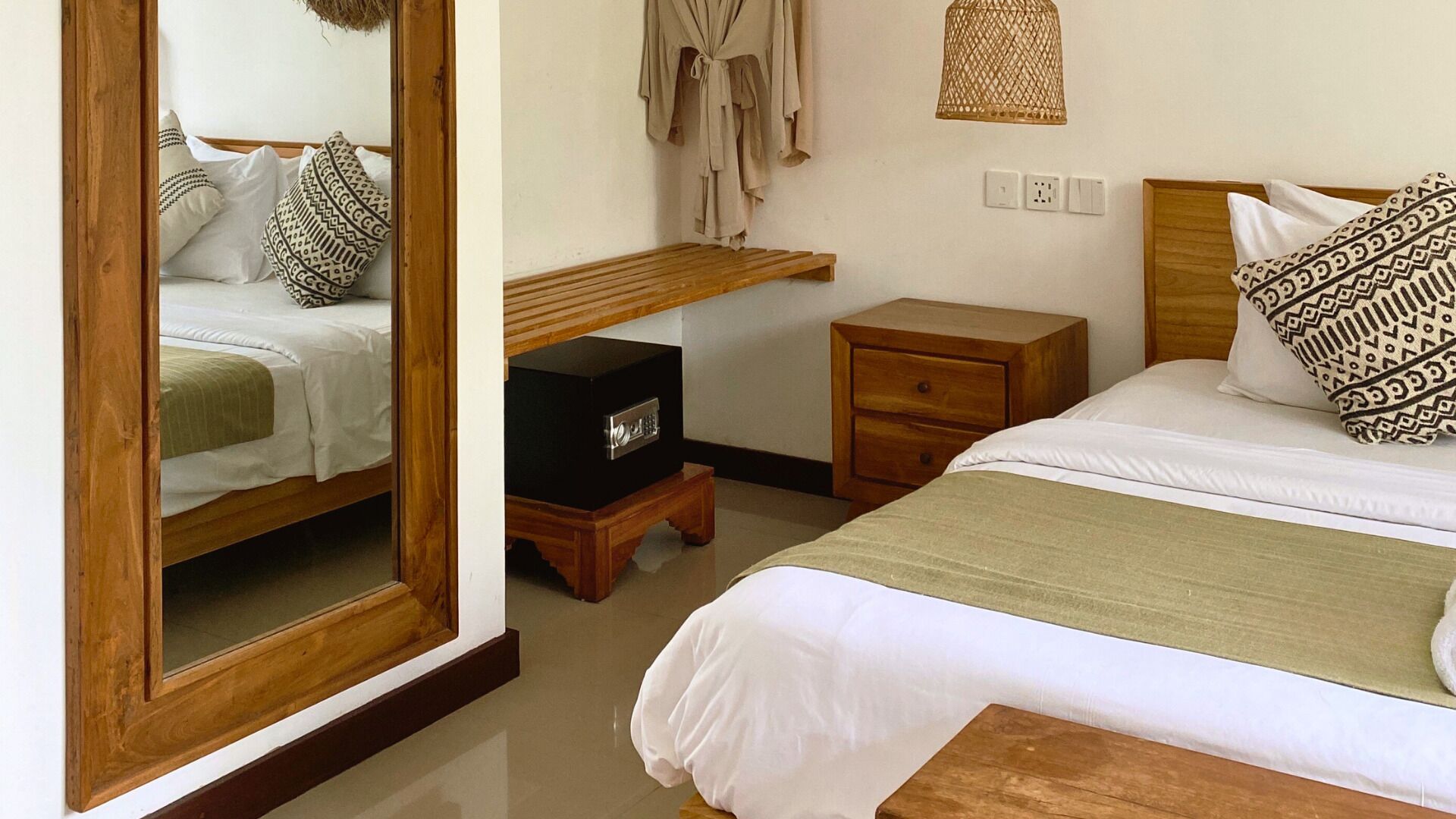 Ein Hotelzimmer mit Bett, Nachttisch, Schminktisch, Spiegel und einer Pendelleuchte.