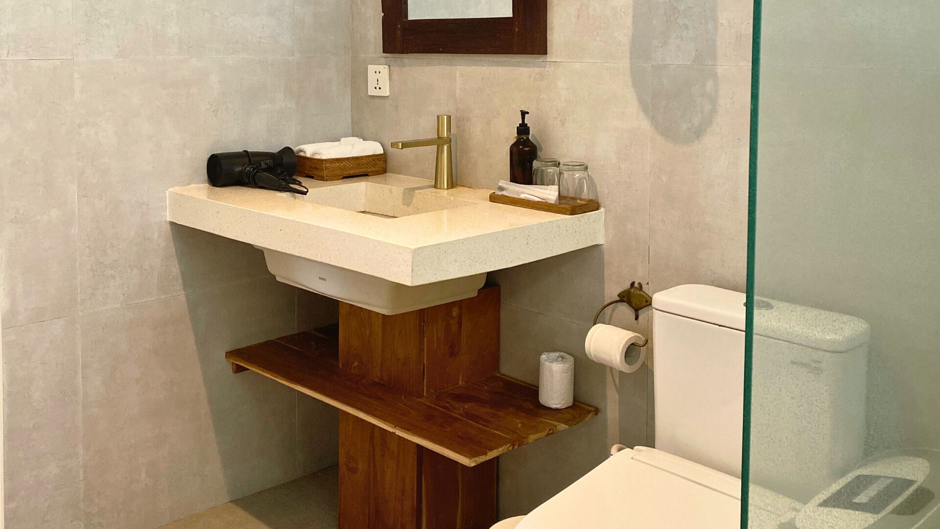 A bathroom with a wooden vanity, a sink, a toilet, and a mirror.