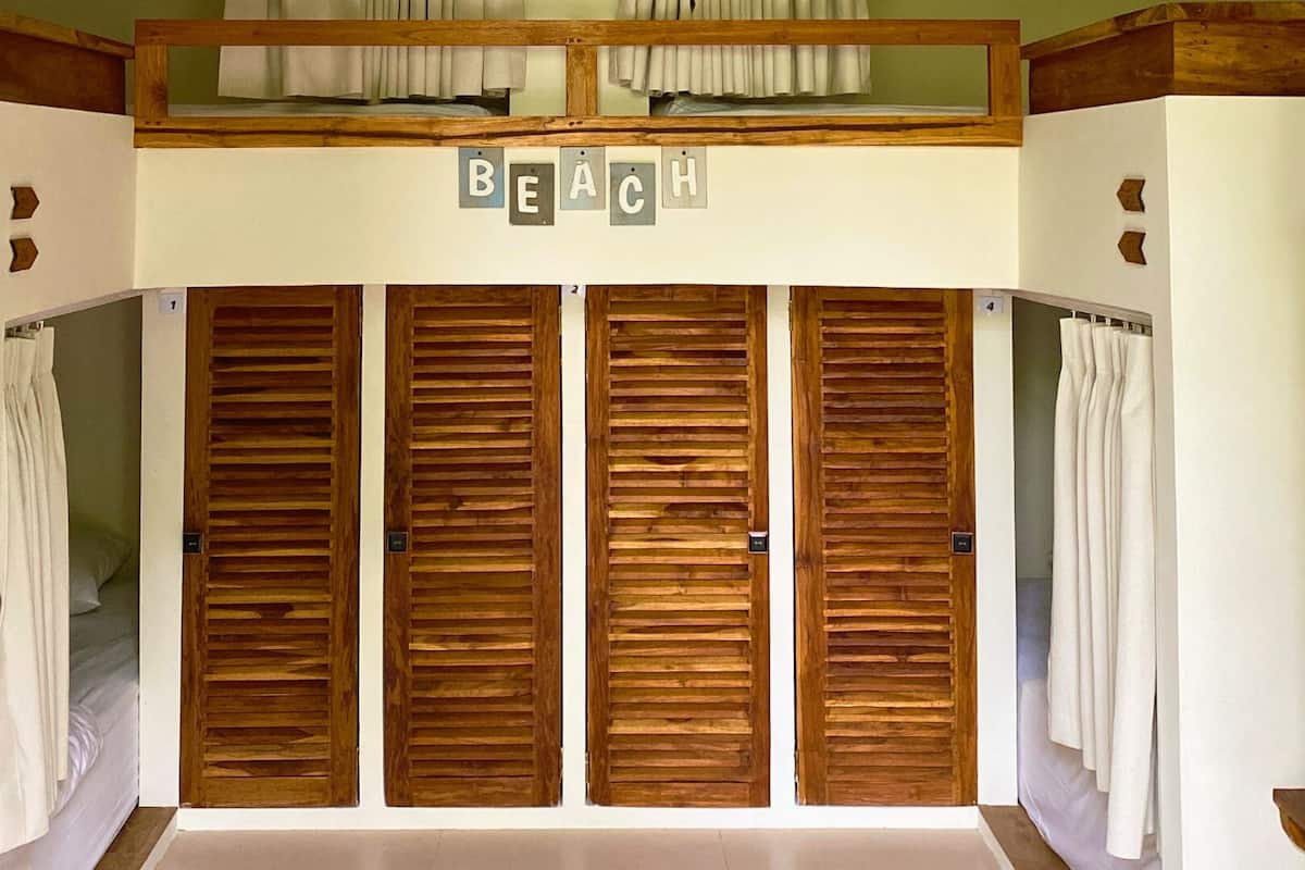 A room with wooden sliding doors, a bed, and a sign above the doors that reads "BEACH".