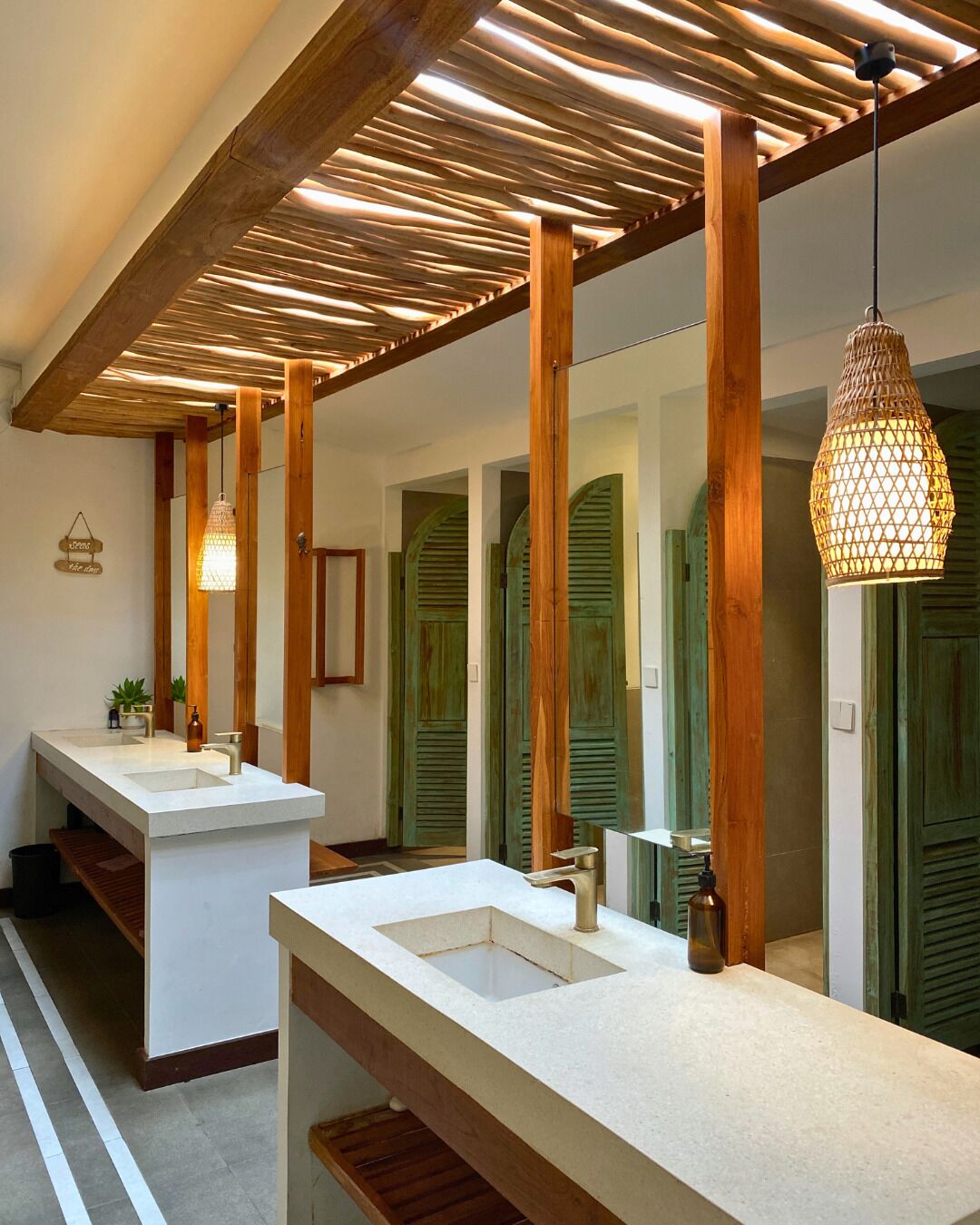 Un baño moderno con vigas de madera, dos lavamanos y una lámpara colgante.