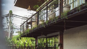 A wooden deck with a table and chairs, a bench, and potted plants. - White Penny Hostel (Keroboken Kelod)