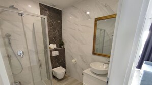 A modern bathroom with a glass-enclosed shower, a white toilet, and a vanity with a large mirror. - Bloom Apartments & Lounge Bar (Vir)