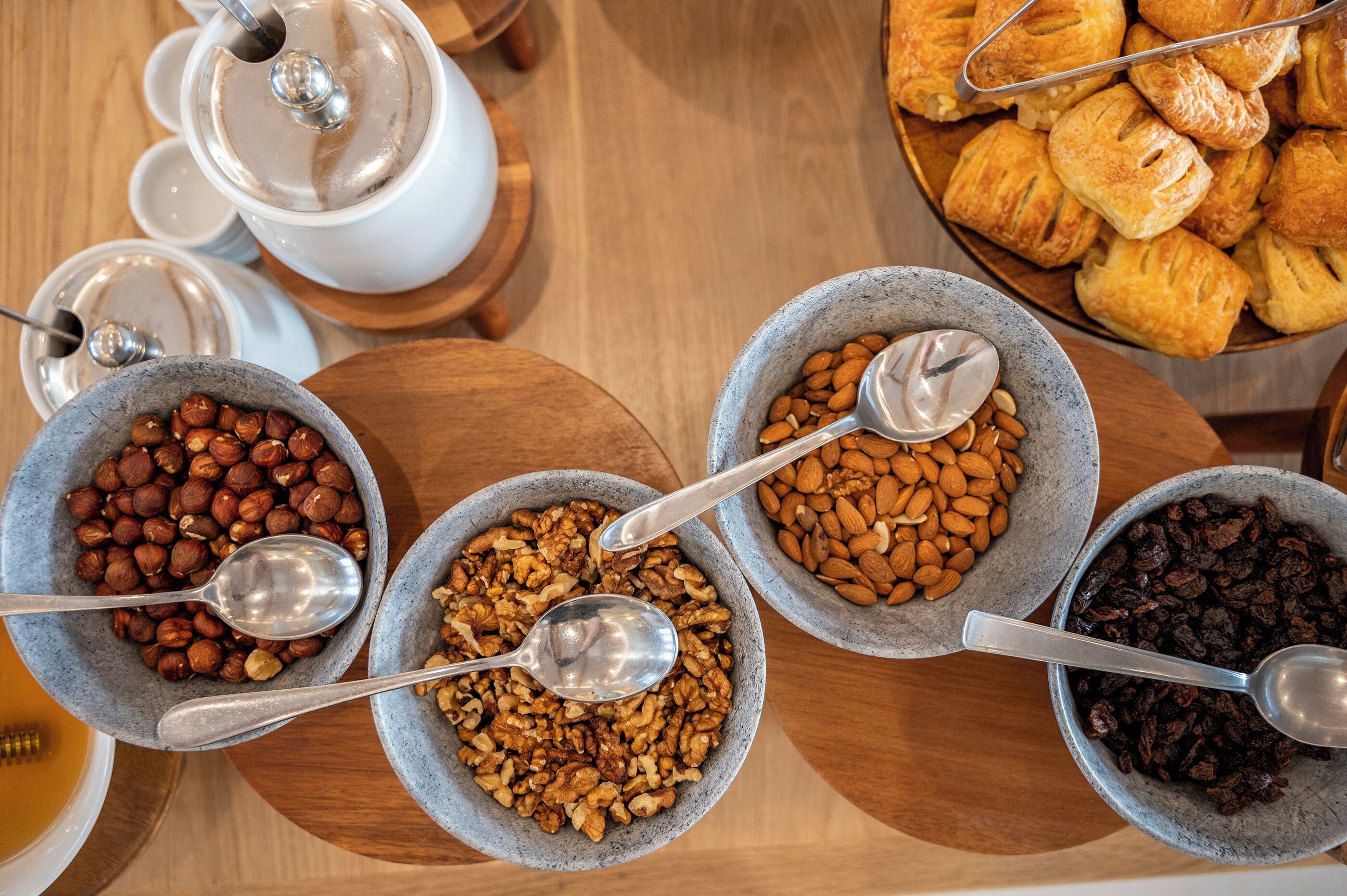 Un bufé de desayuno con diversos frutos secos, frutas deshidratadas y pasteles.