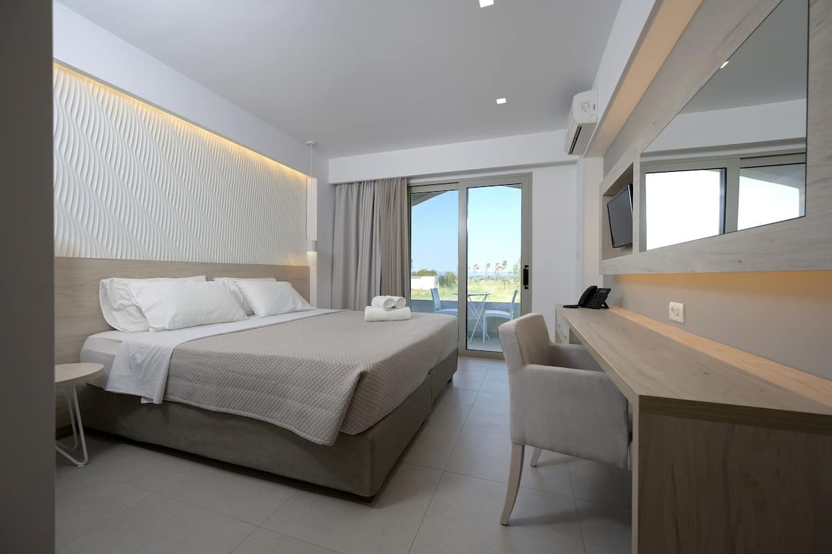 A modern hotel room with a large bed, a desk, and a television.