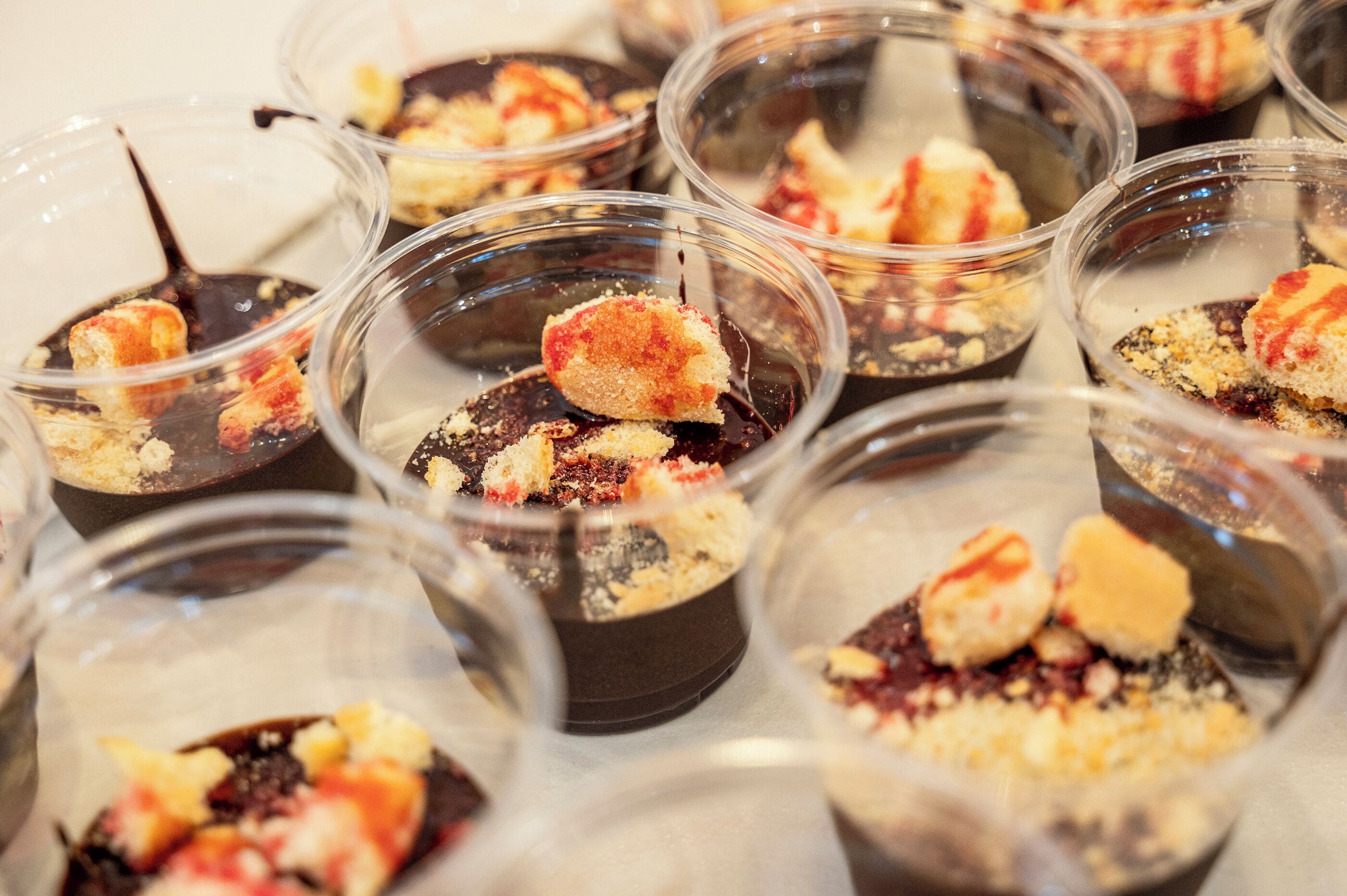 Multiple clear plastic cups containing dessert items with a crumbly topping.