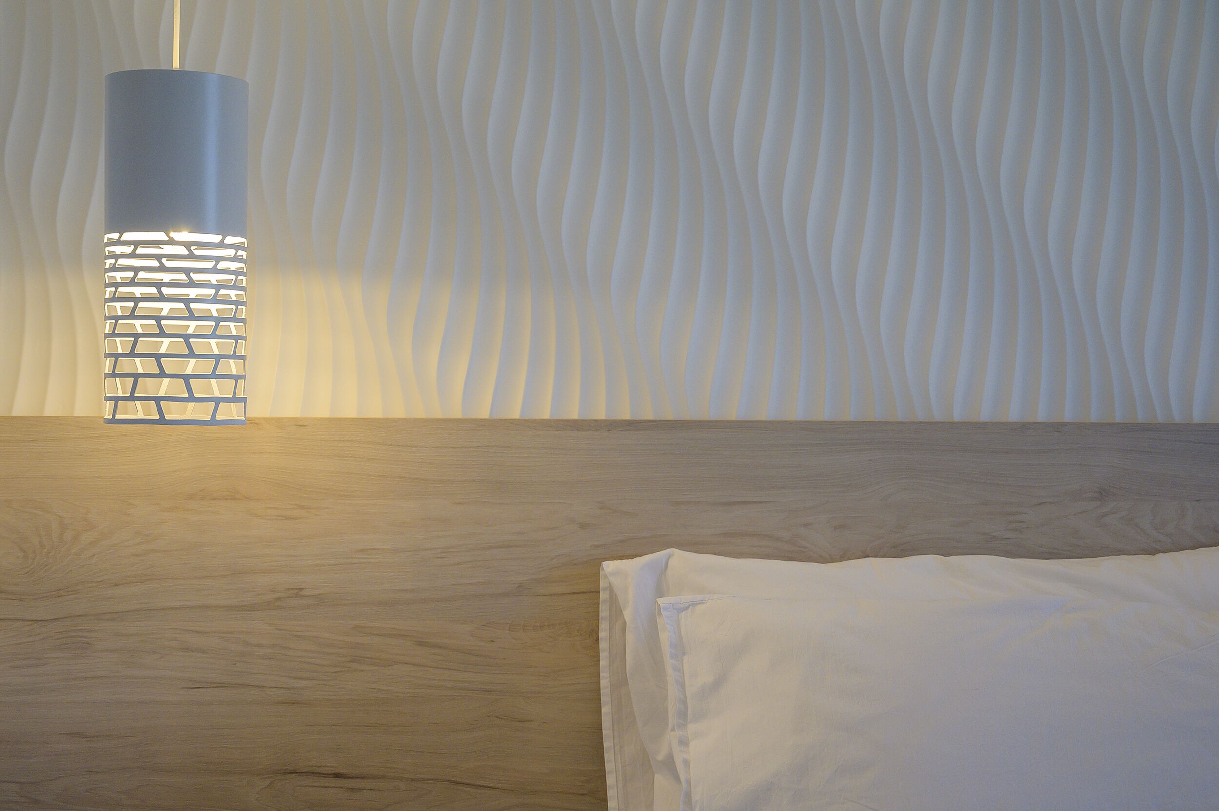A modern room with a wooden floor, a white bed, and a unique wall-mounted light fixture.