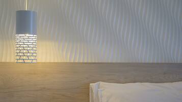A modern room with a wooden floor, a white bed, and a unique wall-mounted light fixture.