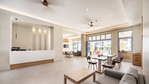 Un vestíbulo amplio con mostrador de recepción, zona de estar y grandes ventanales con vistas al exterior.