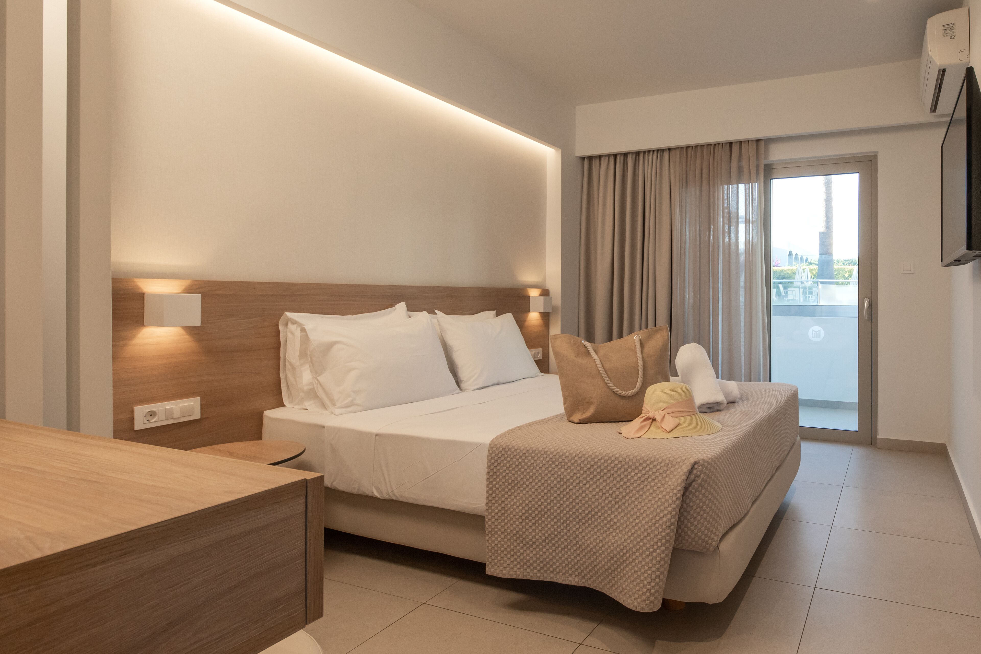 Una moderna camera d'hotel con un letto, un comodino e vista sull'esterno tramite una porta scorrevole.