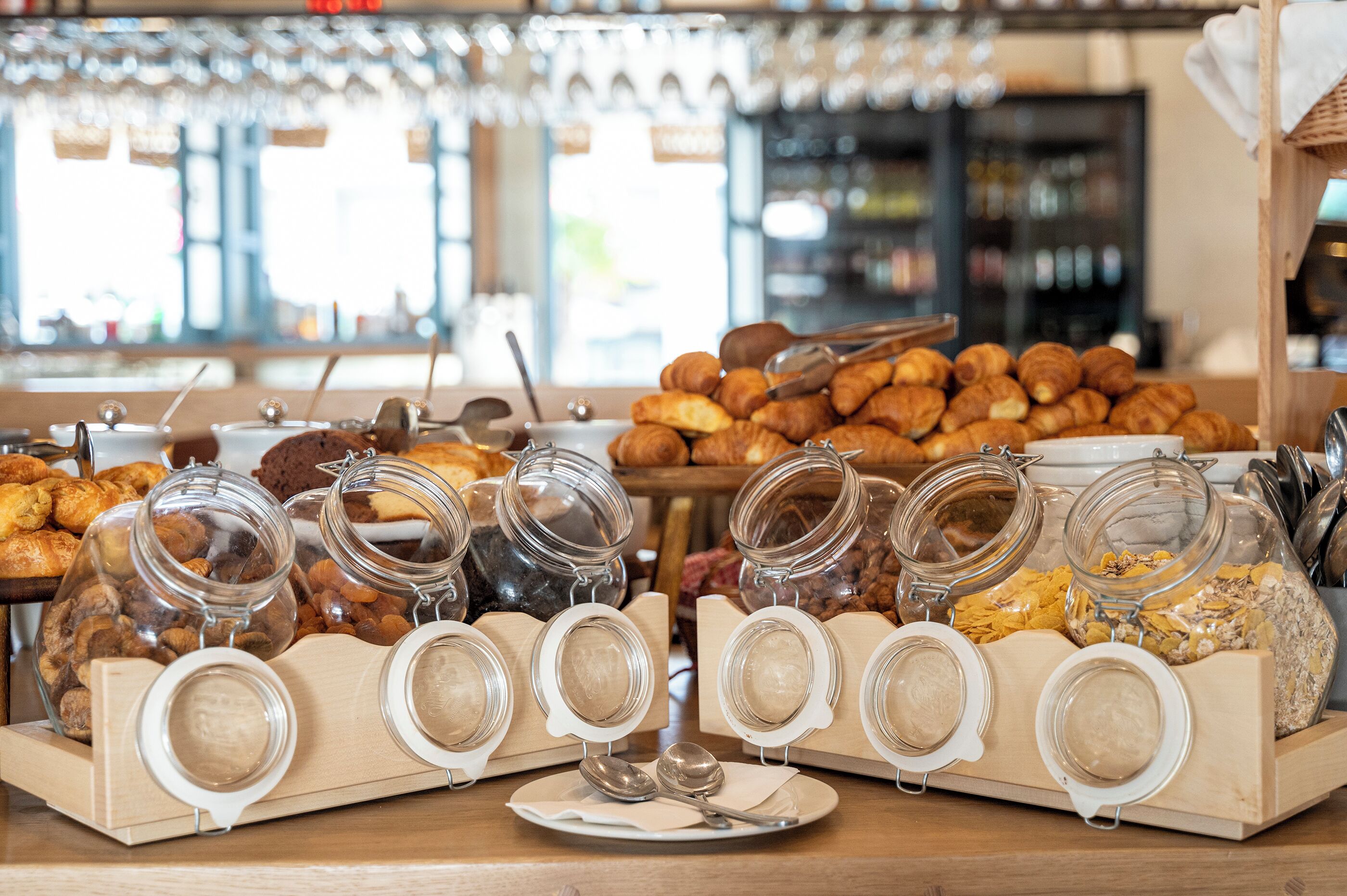 Ein Frühstücksbuffet mit verschiedenen Backwaren und Speisen, die in Gläsern und Körben angerichtet sind.