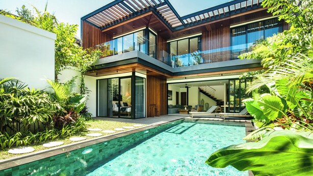 Une maison moderne dotée d’une piscine, de grandes fenêtres et d’un balcon.