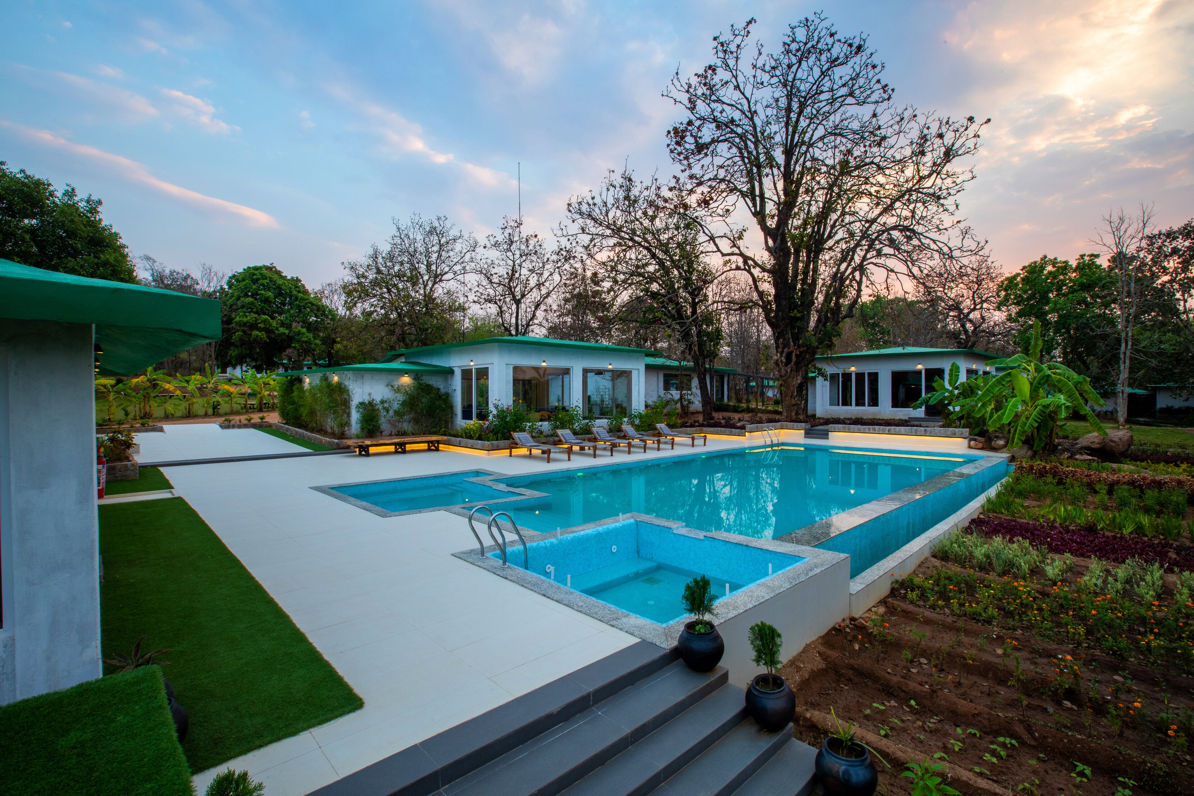 A modern pool area with a large rectangular pool, lounge chairs, and a well-maintained garden.