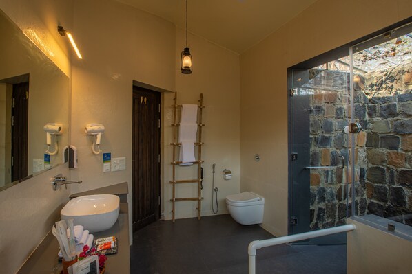 Un baño moderno con un lavabo grande, un espejo, un inodoro y una zona de ducha.