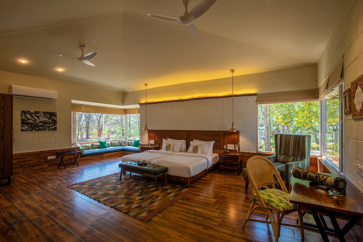 A spacious bedroom with a large bed, a sitting area with a bench, and a dining table.