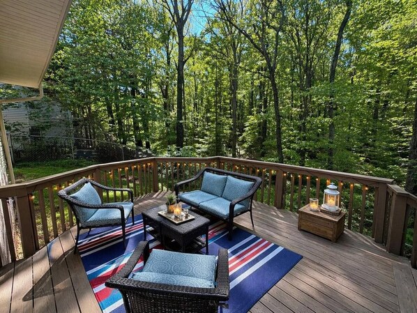 A deck with outdoor furniture, including a sofa and chairs, and a small table with a tray.