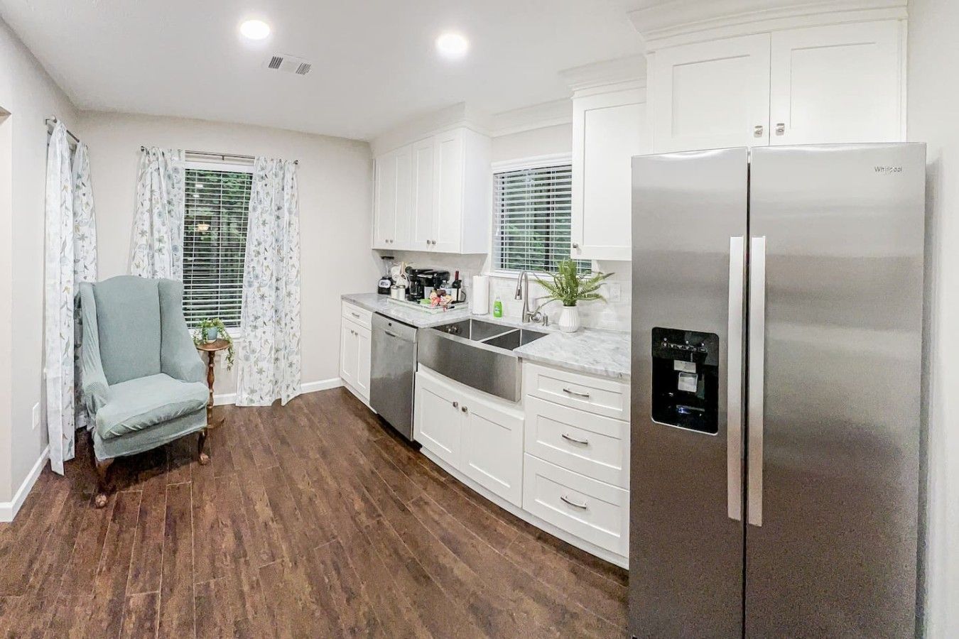 A modern kitchen with white cabinets, a stainless steel refrigerator, and a built-in dishwasher.