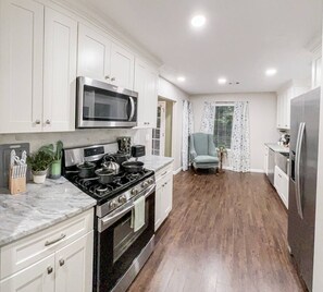 A kitchen with white cabinets, a stove, and a microwave.