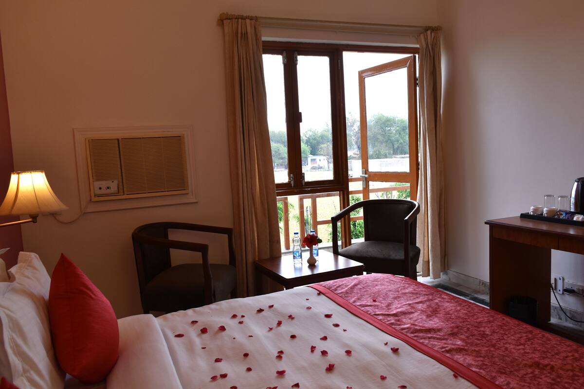 Une chambre d’hôtel avec un lit, un bureau, une chaise et une fenêtre avec des rideaux.