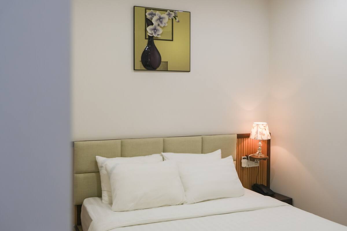Ein Hotelzimmer mit einem Bett, einem Nachttisch mit Lampe und einem Bild an der Wand.