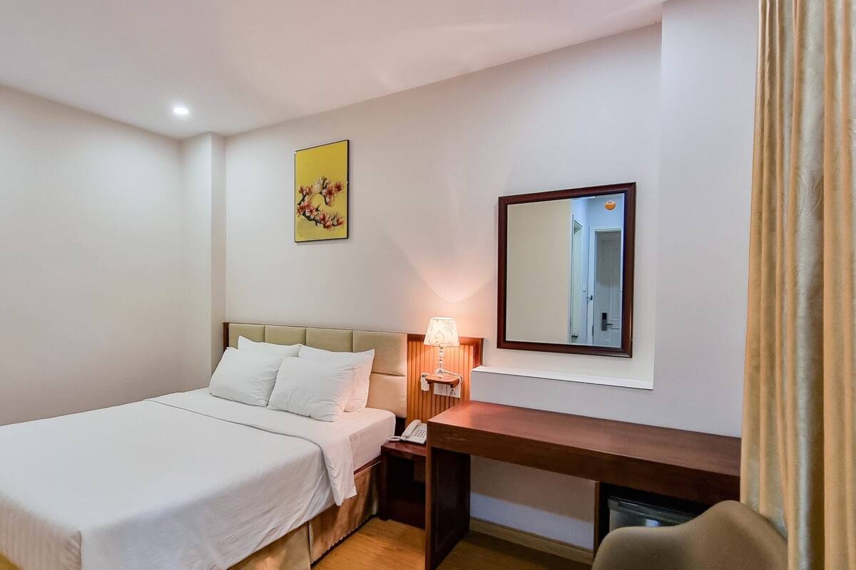 Ein Hotelzimmer mit Bett, Nachttisch, Lampe und einem Spiegel an der Wand.
