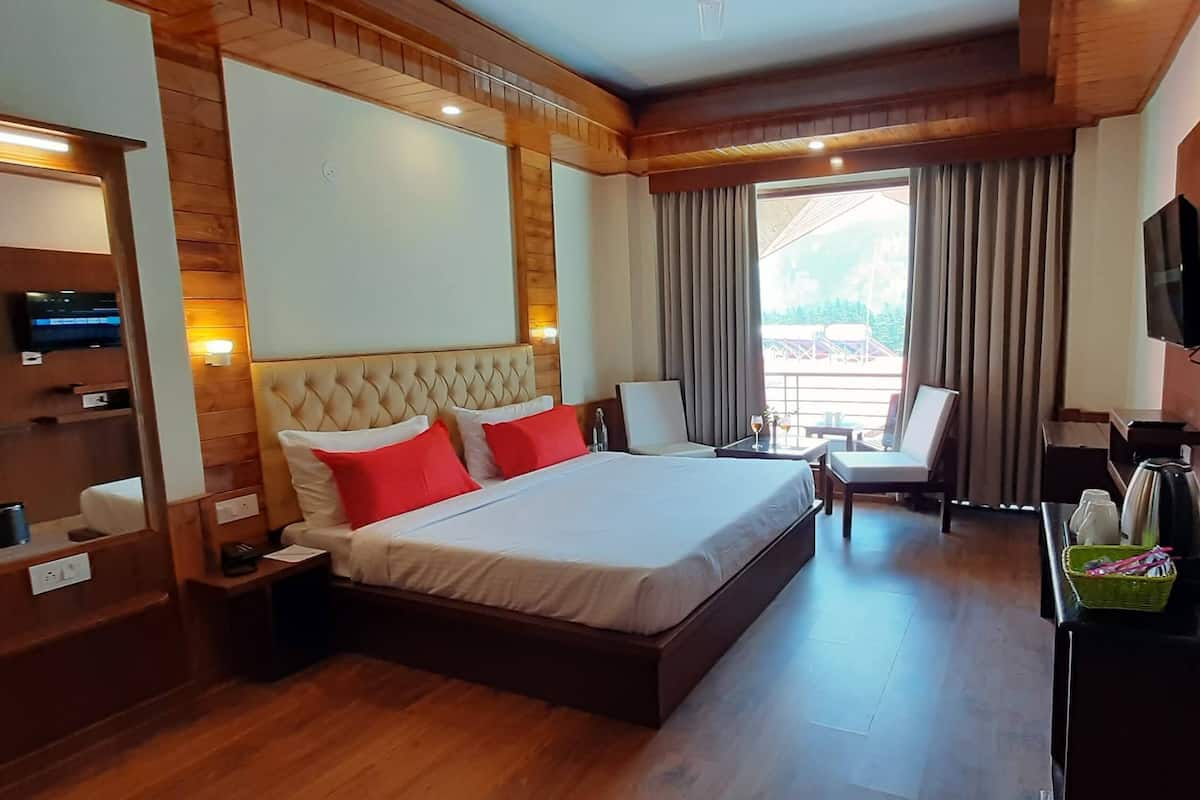 A hotel room with a large bed, wooden paneling, a television, and a balcony with curtains.