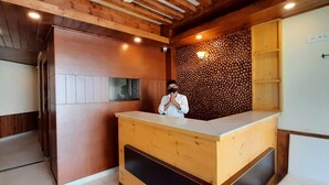 Un área de recepción con un mostrador de madera, una pared con diseño de troncos y un techo con vigas de madera.